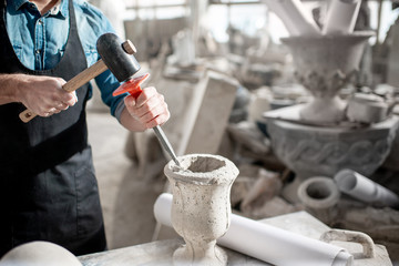 Man working with stone vase at the working place in the old studio. Close-up view with no face