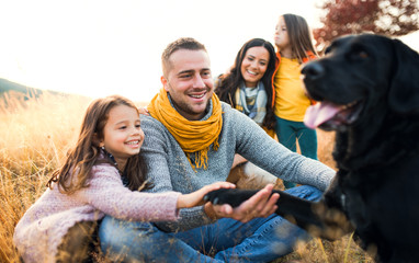 A young family with two small children and a dog on a meadow in autumn nature.