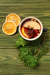 Cup of tasty mulled wine on wooden background