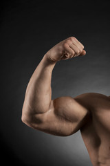 Arm of muscular bodybuilder on dark background