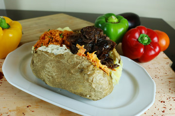 Kumpir - Traditional Turkish meal with baked potato, butter, cheese, bulgur salad, kebab meat and hot spices