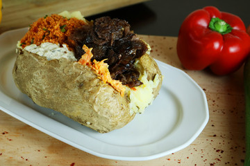 Kumpir - Traditional Turkish meal with baked potato, butter, cheese, bulgur salad, kebab meat and hot spices