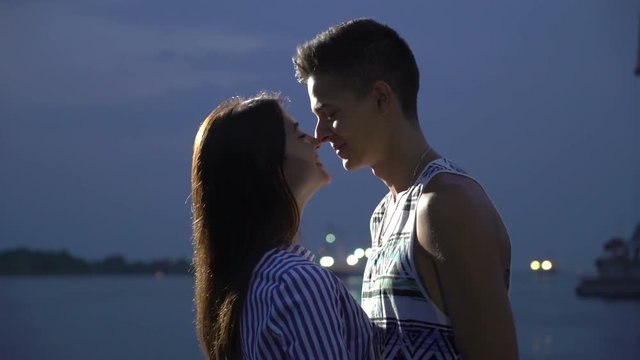 Beautiful girl and her boyfriend smiling and doing an escimo kiss on a quay 