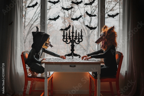 Children in Halloween costumes playing with puzzles by window
