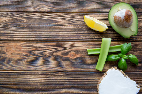 Avocado with cream cheese sandwich, selery sticks and basil leaves on brown table. Space for text.