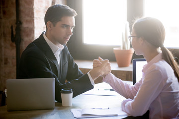 Young man and woman are engaged in arm wrestling, deciding who is stronger at work. Businessman and...