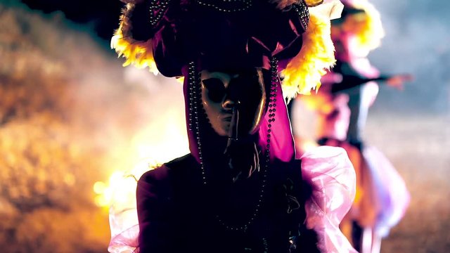 The face of the girl at the masquerade in a Venetian suit hides a mysterious mask. Dance with fire in the night. Concept idea for dance