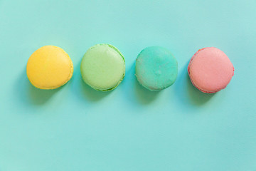 Sweet almond colorful pink blue yellow green macaron or macaroon dessert cake isolated on trendy blue pastel background. French sweet cookie. Minimal food bakery concept. Flat lay top view copy space