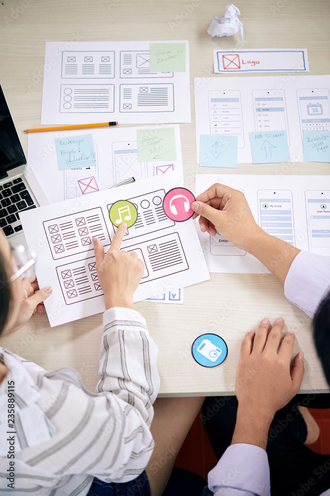 Canvas Prints crop shot from above of man and woman choosing colorful icons for new app working with papers at des