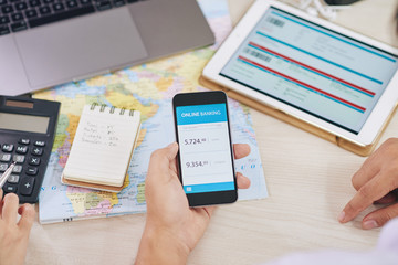 Crop shot from above of coworkers watching smartphone with online banking app 
