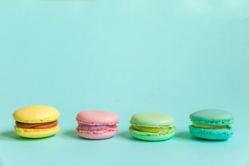 Sweet almond colorful pink blue yellow green macaron or macaroon dessert cake isolated on trendy blue pastel background. French sweet cookie. Minimal food bakery concept. Flat lay top view copy space
