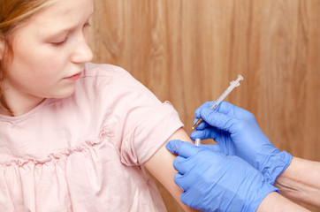 Doctor injecting a vaccine in arm of tween girl - child vaccination concept