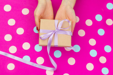 Woman hands holding gift box on pink background