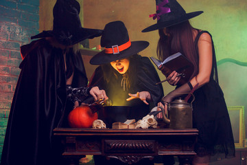 Portrait of three witches with book of boiling potions at cauldron