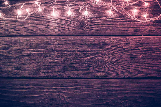Toned photo of wooden table with burning New Year's garland.