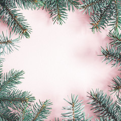 Christmas composition. Frame made of fir tree branches on pastel pink background. Christmas, winter, new year concept. Flat lay, top view, copy space, square
