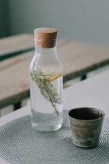 Infused fresh water with lemon and thyme in a glass decanter on the table in the interior of the...