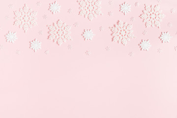 Christmas or winter composition. Border made of snowflakes on pastel pink background. Christmas, winter, new year concept. Flat lay, top view, copy space