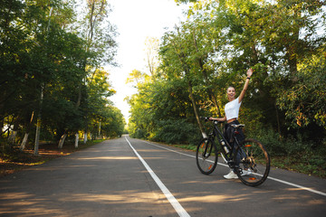 Beautiful young fitness girl walking with bicycle