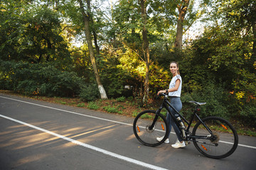 Fototapeta premium Beautiful young fitness girl walking with bicycle