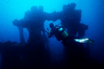 Naklejka na ściany i meble photographer diver taking a picture of a wreck