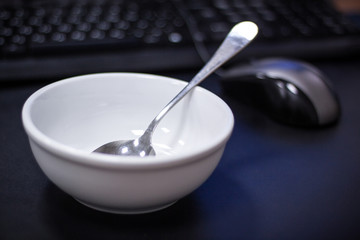 snack at the workplace at the office worker's computer. Diet porridge in a white plate on the table. computer mouse keyboard in the background