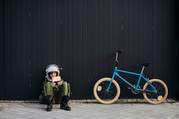 Portrait of a boy on a bicycle in street astronaut dress, playing a videogame