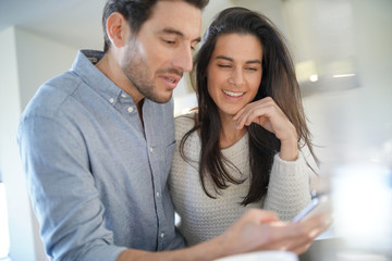  Stunning couple happily looking at cellphone in kitchen