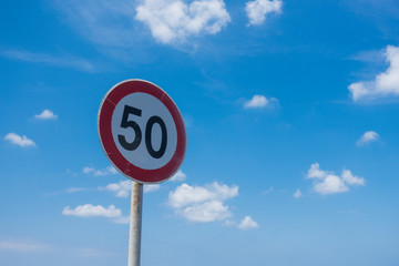 low angle view of road sign 50km/h against clear blue sky