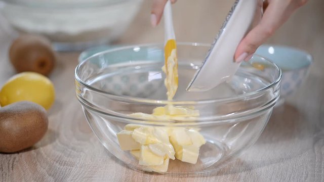 Women hands putting soft butter in bowl. Step of making cooking cake, preparing dough. Ingredients: butter, sugar, eggs.