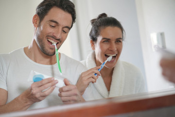  Fun attractive couple brushing teeth together