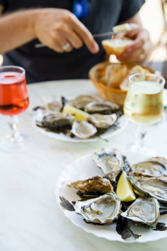 Raw oysters served in a french restaurant with lemon slices, wine, baguette and butter