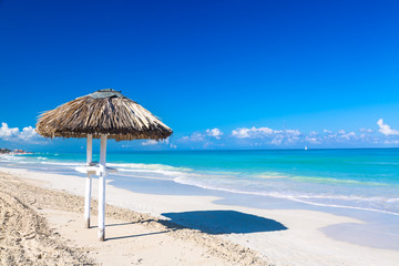 Straw umbrella on empty seaside beach in Varadero, Cuba. Relaxation, vacation idyllic background.