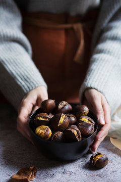 Woman holding a bowl with roasted chestnuts