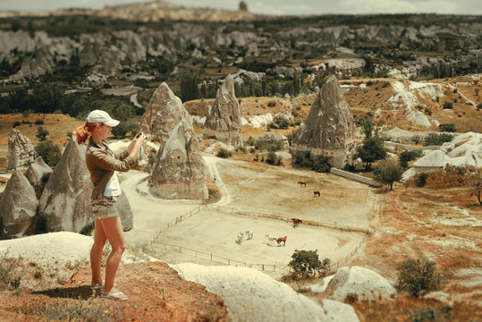 Woman watching and taking pictures of horses in Cappadocia, Turkey