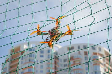 Small racing drone is stuck in the net. Accident during the flying drone