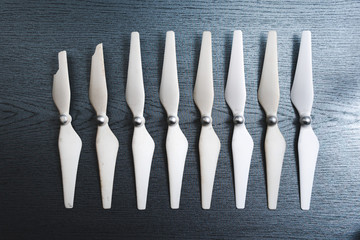 Top view. Drone components, propellers and one broken, aerial video concept pilot school mistakes and get experience, background wooden table not like everyone else, an outcast © Sergey