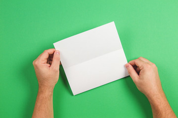 Mock up template. White blank brochure booklet in the hand on green background