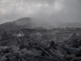 dark place. steam rises above the cooling lava flow of Tolbachik volcano