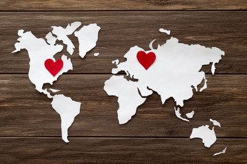 Red felt hearts and world map cutted from white paper on the wooden background. Long-distance relationships concept - Russia and United States. Flat lay, top view, copy space, mock up