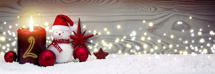 Christmas background with second Advent candle and Snowman with red decoration.