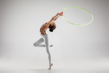 The teen female little girl doing gymnastics exercises with hoop isolated on a gray studio background. The gymnastic, stretch, fitness, lifestyle, training, sport concept