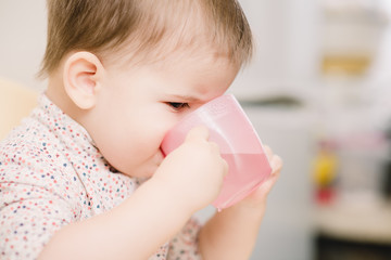 child in the kitchen drinking from a cup of water