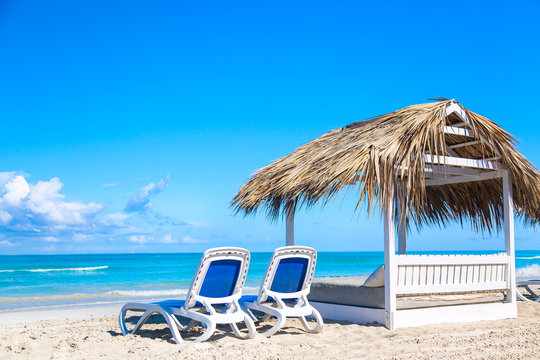 A sun loungers near bed on the sandy beach by the sea and sky. Vacation background. Idyllic beach landscape.