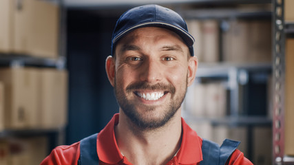 Portrait of Smiling Uniformed Worker. In the Background, Room with Shelves Full of Cardboard Box...