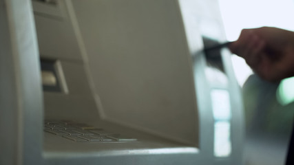 Woman inserting credit card into atm to check her money balance, easy banking