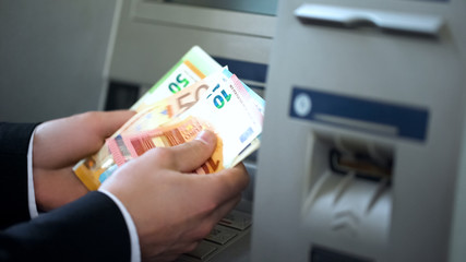 Man counting euros withdrawn from ATM, 24h service, easy banking operation