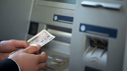 Male getting Japanese Yen from automatic teller machine, cash withdrawing