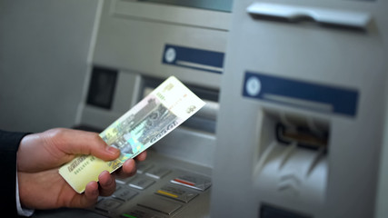 Male getting Russian rubles from automatic teller machine, cash withdrawing