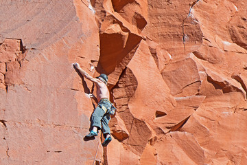 A climber ascends the red rock face of Elephant Butte in Sedona, Arizona